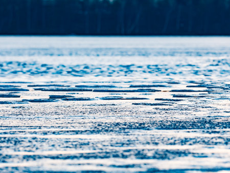 Bubbles and pieces of clear natural ice on frozen lake in evening sun. The melting changet the flat surface of ice to puddle with shardsの写真素材