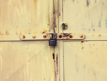 Rusty metal latch with lock housing of cargo garage or warehouse. Corrosion stains on metal sheet...