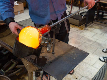 Glass blower forming a beautiful piece of glass. A glass crafter is blowing and shaping new art...