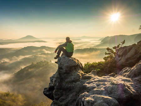 Hiking on a mountain ridge in the summit of clouds. A happy man silhouette alone