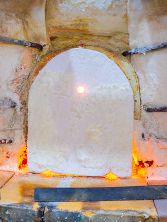 Shining glass blowing furnace behind cover. Gas kiln in glass design studio, manual production of glass artの写真素材
