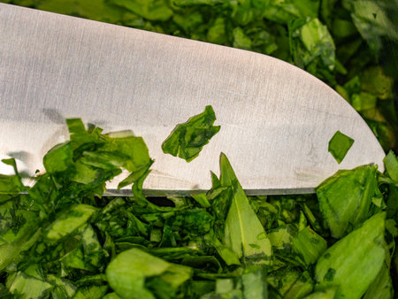 Freshly chopped ramsons leaves or wild bear garlic leaves in chrome bowl. Wooden table, cold stainless steel knife and wild garlic leaves in kitchen. Top view.の写真素材