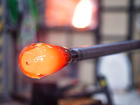 Manual shaping hot glass in art studio. Man designer is creating a fluted bowl from this piece of molten glass.の写真素材