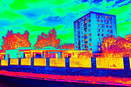 High flat house behind family house in Infrared thermovision scan showing lack of thermal insulation. Infra or thermography photoの写真素材