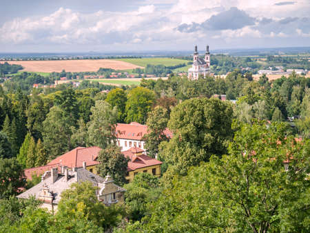 Luze village with Hamzova hospital roofs and baroque church above park.