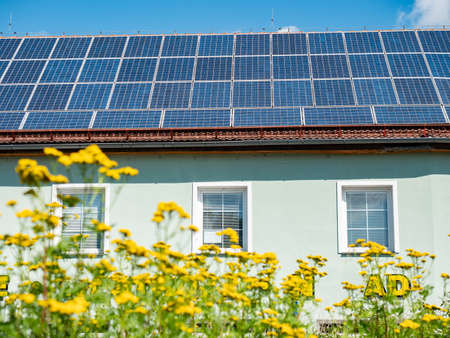 Electric solar panels on the roof of a beautiful modern house. Rays of the sun reflting in the blue cells of panels.の写真素材