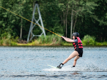 Straz, Czechia. 29th of July, 2021. Wake boarding boy on lake, the forest in blurry background.のeditorial素材