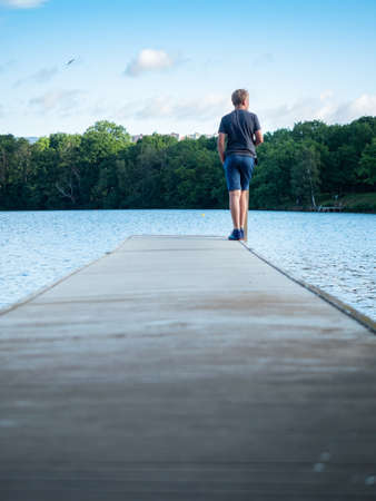Boy stay on swimming pier above alum lake Kamencove jezero in Chomutov town.