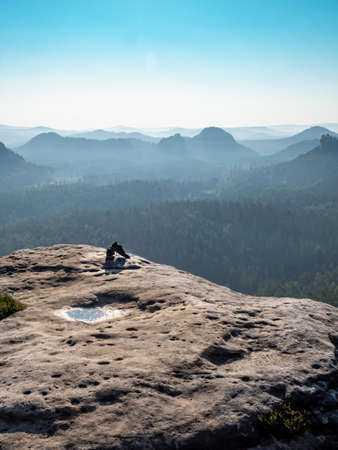 Sweaty running shoes on the edge of a rock. The top of the mountain above a long valley.の写真素材