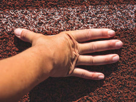 Female wrist with outstretched fingers at the starting line of a running track. Starting possition conceptの写真素材