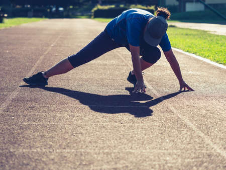 Sports woman stretching legs muscles and bend back before condition run on school stadiumの写真素材