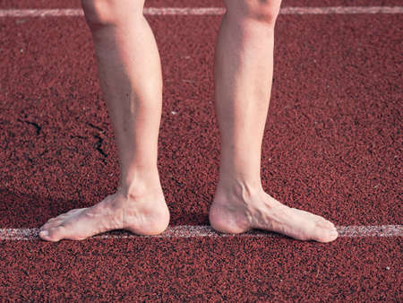 Barefeet woman stay at staring lin on stadiom. Naked feet with embossed veins, old hardened muscles.