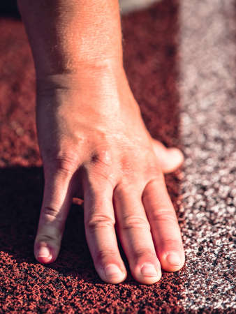 Starting line with outstretched fingers. Stadium white starting line of running track.の写真素材