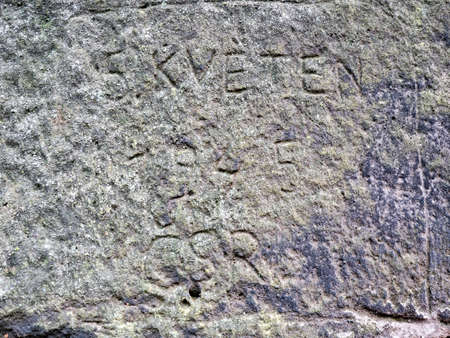 Letters and numbers engraved by vandals into sandstone rock.