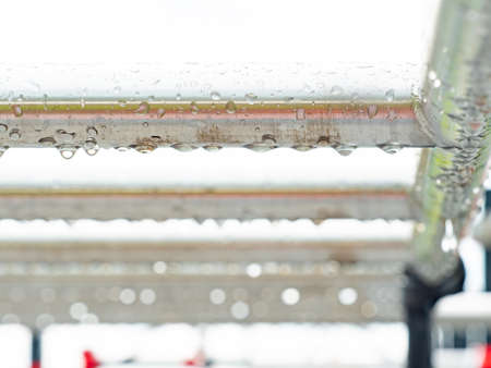 Detail of stainles steel construction with rain drops. Gray white sky in backgroundの写真素材