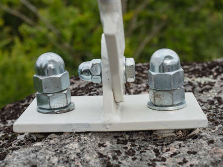Detail of zinc coated cup head nuts screwed on screw anchors in granite stone.の写真素材