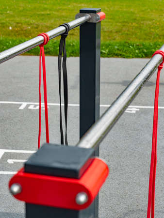 Exercise and stretching rubber elastic bands hanging on a workout rail. Exercise equipment after the rain without peopleの写真素材