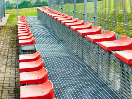 Red tribune chairs. Plastic stadium seats in two rows.の写真素材
