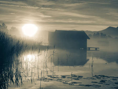 Romantic sunrise reflection on lake Kochelsee against boathouses. Early summer morning view, Bavaria, Germany. BW, Black and white,の写真素材