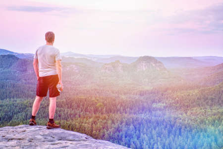 Hiker or running man hold plastic bottle with drink on rocky edge at misty mountains backgroundの写真素材