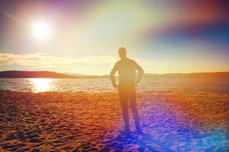 Runner man stand for deep breath moment whithin regular morning run on the beachの写真素材