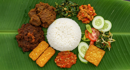AI generative photo of traditional Indonesian Nasi Campur meal served on banana leaf with rice, tempeh, sambal, vegetables, and fried chicken. Perfect for culinary, and culture.の素材