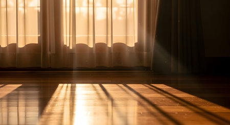 Soft golden morning sunlight shining through window curtains and casting warm shadows on a wooden floor. Peaceful and serene atmosphere perfect for lifestyle and relaxation themes.の素材
