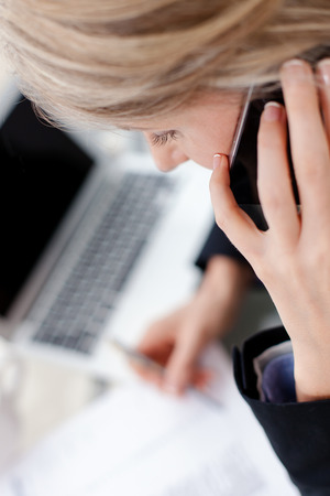 Close-up portrait of a successful business woman talking on cell phone in the office の写真素材