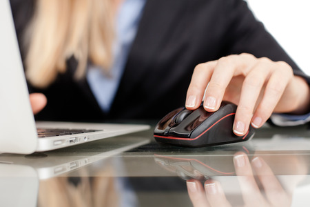 Close-up of working businesswoman  Woman s hands touching computer mouse and keys of silver opened laptop の写真素材