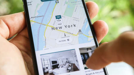 NEW YORK CITY, NY â December 1, 2019: Woman trying to book home apartment room in New York City using Airbnb appのeditorial素材