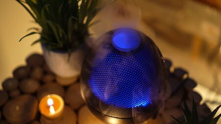 Aroma electric oil diffuser lamp, candles on wooden table in room. Aromatherapy.