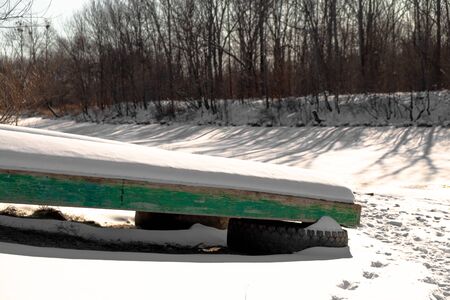 Wooden boat on a frozen river in a Russian village.の写真素材