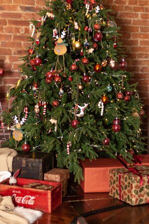 Gift boxes wrapped around the Christmas tree on the background. Cozy house is decorated to celebrate the New yearのeditorial素材