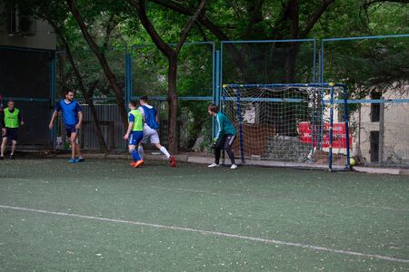 Street domestic playing soccer. Young guys play soccer on a green grassのeditorial素材