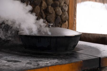 Preparation of shurpa in a cauldron on a Russian stove on an open fireの写真素材
