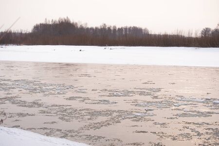 Mountain Russian river in winter. Snow on the shore. Rapid flow of ice waterの写真素材