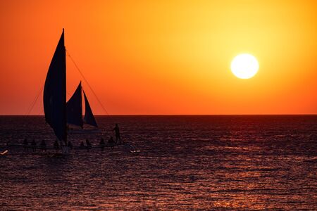 Sunset on the background of bottles standing on the bar. The sun passes through the bright glass of the bottles. Background image for the screensaver.の写真素材