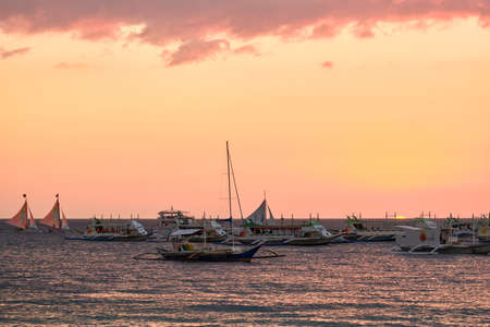Boracay, Philippines - Jan 23, 2020: Sunset on the background of bottles standing on the bar. The sun passes through the bright glass of the bottles. Background image for the screensaver.のeditorial素材