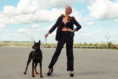 Khabarovsk, Russia - Sep 09, 2018: Fashion girl with red hair with a Doberman on the streetのeditorial素材