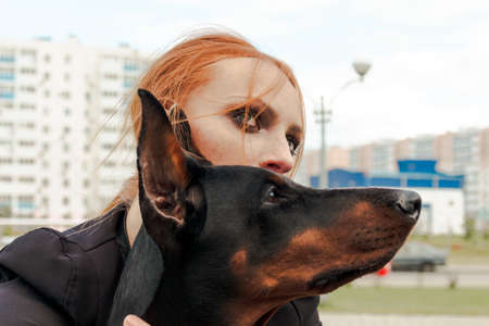 Khabarovsk, Russia - Sep 09, 2018: Fashion girl with red hair with a Doberman on the streetのeditorial素材