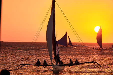 Boracay, Philippines - Jan 23, 2020: Sunset on Boracay island. Sailing and other traditional boats with tourists on the sea against the background of the setting sun.のeditorial素材