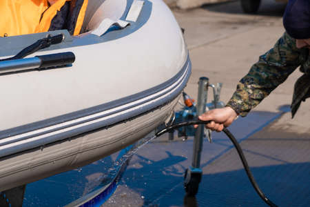 A man washes a rubber hose boat after going to sea. Drops of water scatter from the boat.