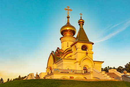 Beautiful view during sunset at the temple of St. Seraphim of Sarov in the city of Khabarovsk. A beautiful green lawn in the foreground. Religious architecture, buildings and traditions. Russia.の写真素材