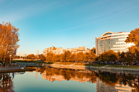 City ponds in the autumn. Trees covered with yellow and orange leaves are reflected in the water. Blue sky.のeditorial素材