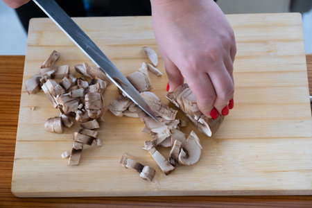 Woman cutting mushrooms on wooden boardの写真素材