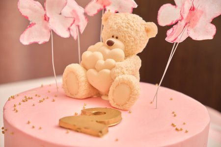 Round pink birthday cake for a child in 2 years. White chocolate bear with hearts on the cake.の写真素材