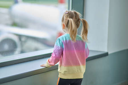 Khabarovsk, Russia - May 25, 2021: a little girl at the airport looks at the planes.の写真素材