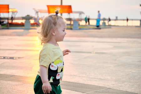 A little girl walks at sunset along the Amur River embankment in the city of Khabarovsk. Russia.の写真素材
