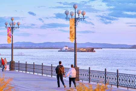 Khabarovsk, Russia - Sep 29, 2021: Sunset on the Amur River embankment in Khabarovsk. Sunset over the horizon. Leaves of autumn trees on the backgroundのeditorial素材