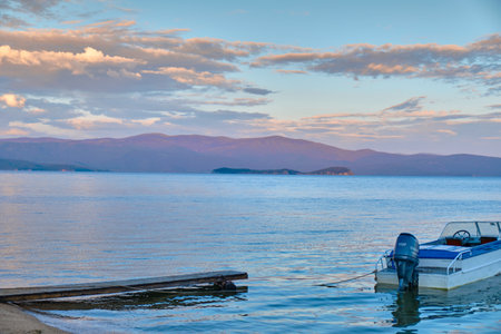 Kurbulik, Republic of Buryatia, Russia - July 11, 2022: The shore of the Holy Nose Peninsula in the Chivyrkuy Bay of Lake Baikal with boats tied up during a colorful sunset.のeditorial素材